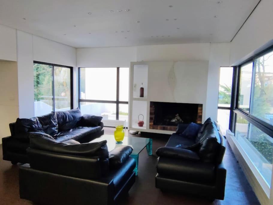 a living room with black leather couches and a fireplace at Maginifique villa d&#39;architecte sur les bords de Marne tout près de Paris in Le Perreux-Sur-Marne