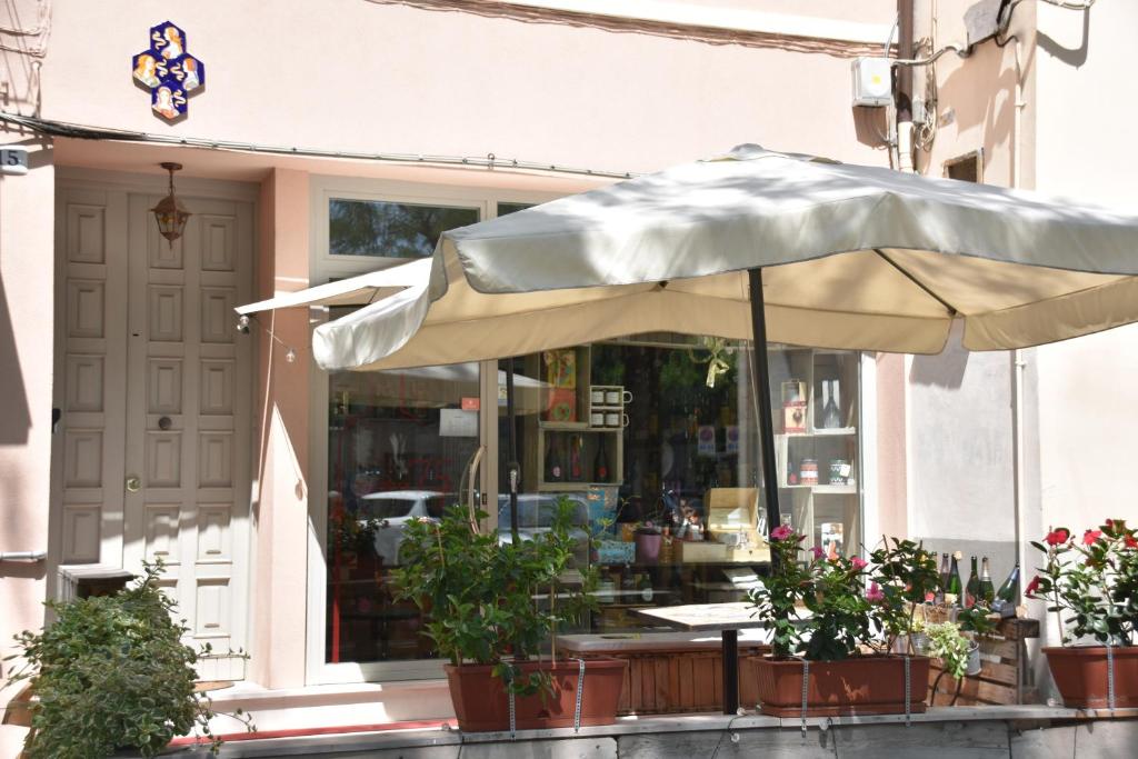 une table avec un parasol devant un magasin dans l'établissement Le Dame Manfrede, à Faenza