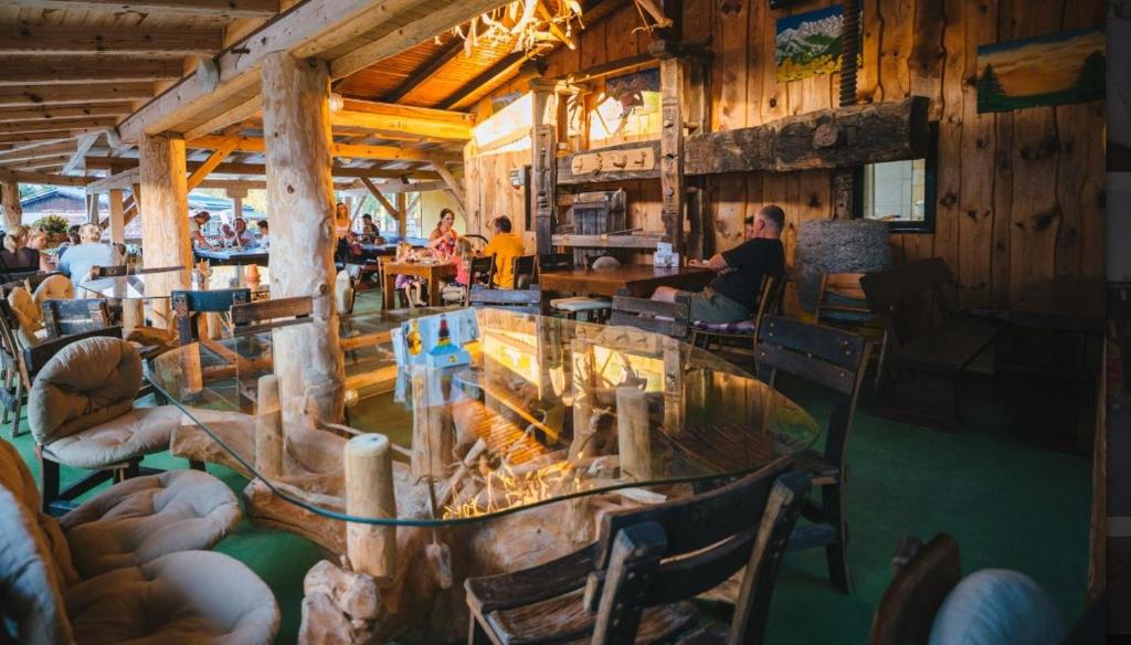 a restaurant with a glass table and chairs and people at Forest Lodge Camping Menina in Rečica ob Savinji