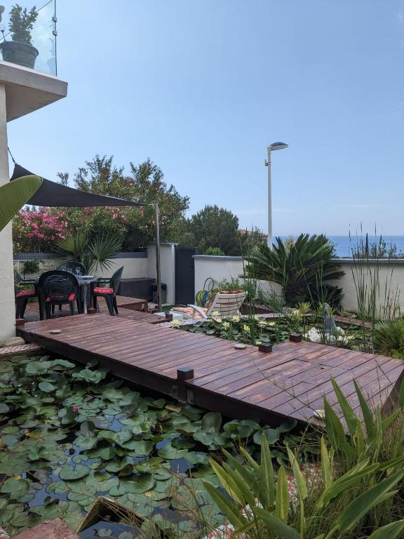 une terrasse en bois avec des chaises et un bassin de nénuphars dans l'établissement Havre de Paix sur la Côte Bleue, à Sausset-les-Pins