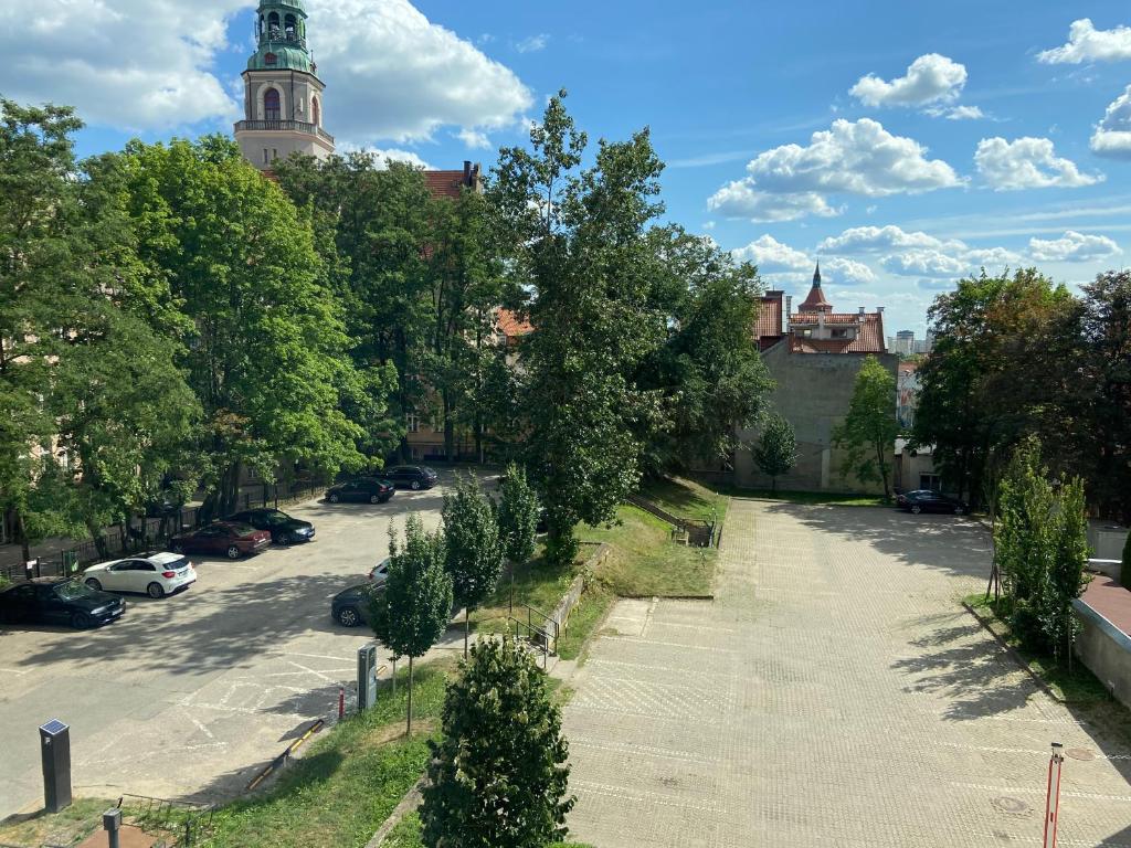 a street with trees and a building with a tower at Komfortowe mieszkanie w samym centrum. in Olsztyn