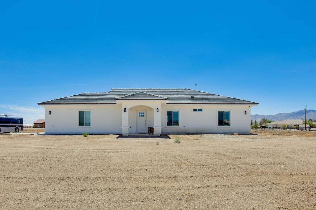 a white house in the middle of a field at Serene Pahrump Cottage with Mountain Views! in Pahrump