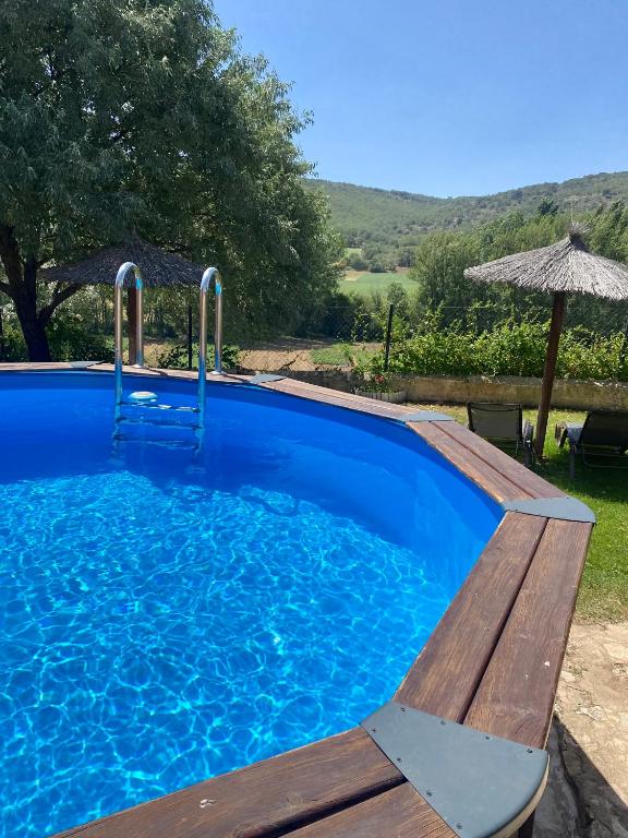 a blue swimming pool with a bench and an umbrella at El Balcón De Alboreca in Sigüenza