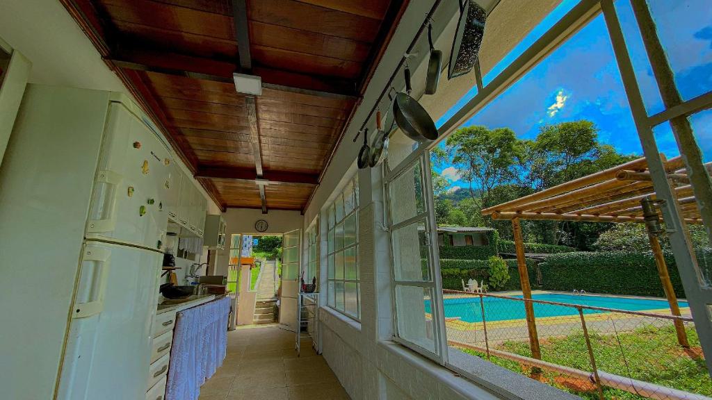 uma cozinha exterior com vista para uma piscina em Canto da Araponga em São Roque