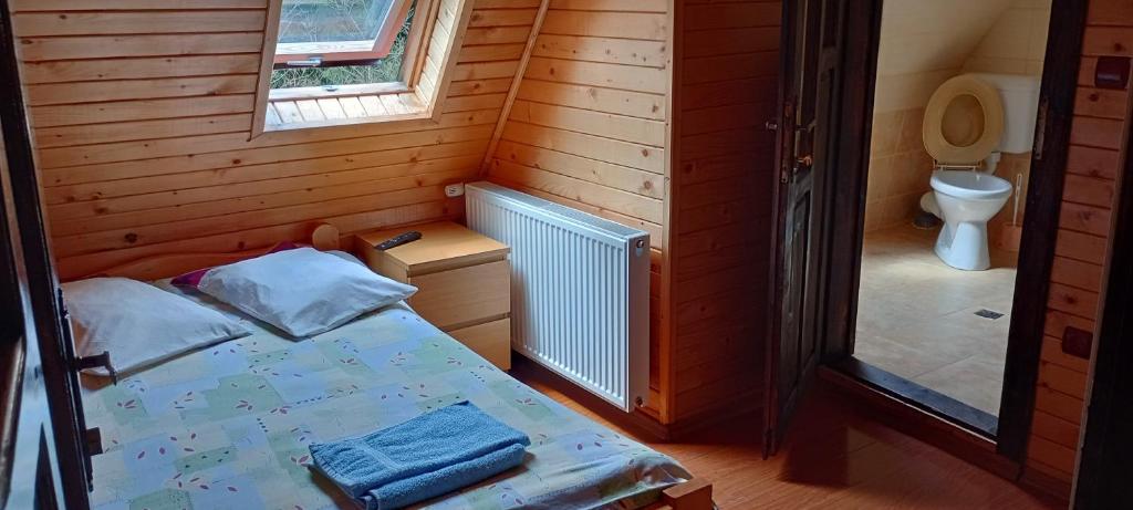 a small room with a bed and a toilet at La Malul Arieșului in Gîrda de Sus