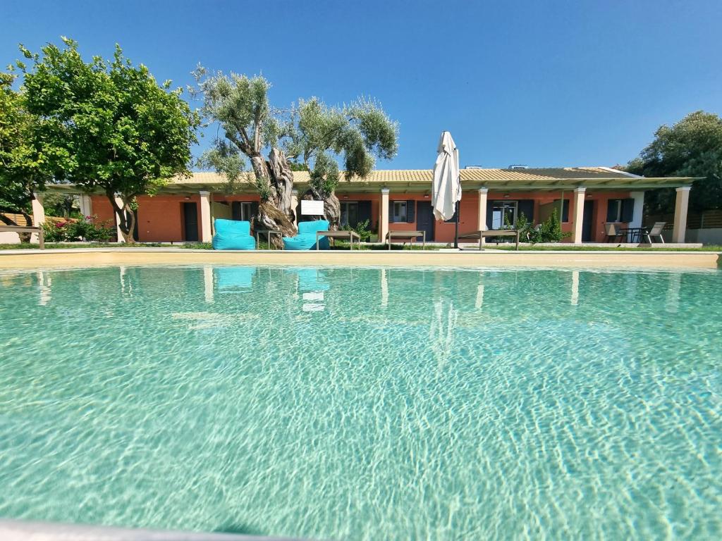 a large swimming pool with an umbrella and a house at Seadrop Suites in Lefkada Town