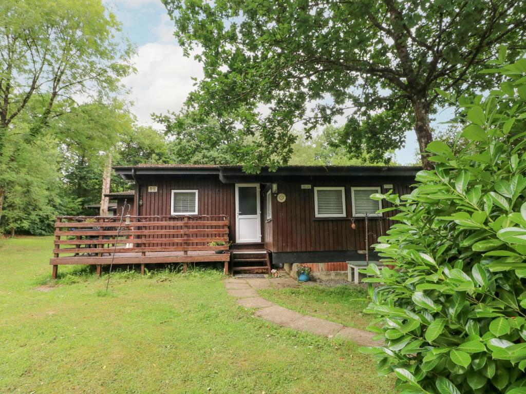 una pequeña casa con un banco delante en Doirewood, en Newcastle Emlyn