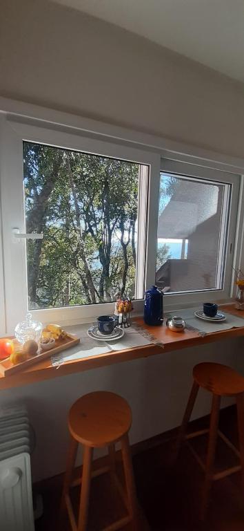 encimera de cocina con 2 ventanas y 2 taburetes en Recanto Ninho das Aguias, en Nova Petrópolis