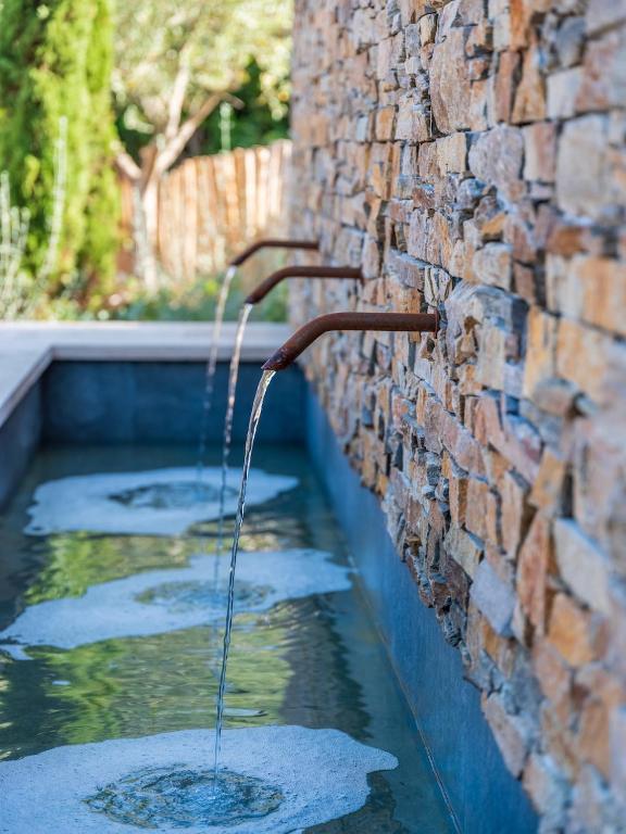 a water fountain on the side of a brick wall at Hôtel L'Escalet in Ramatuelle