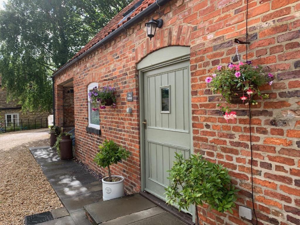 a brick house with a green door and flowers at The Bolthole barn with wood-fired hot tub in Glentworth