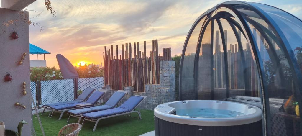 e patio con vista su una vasca idromassaggio e sedie. di Sunset sea view & garden Spa Cala Tarida 6p max a Cala Tarida