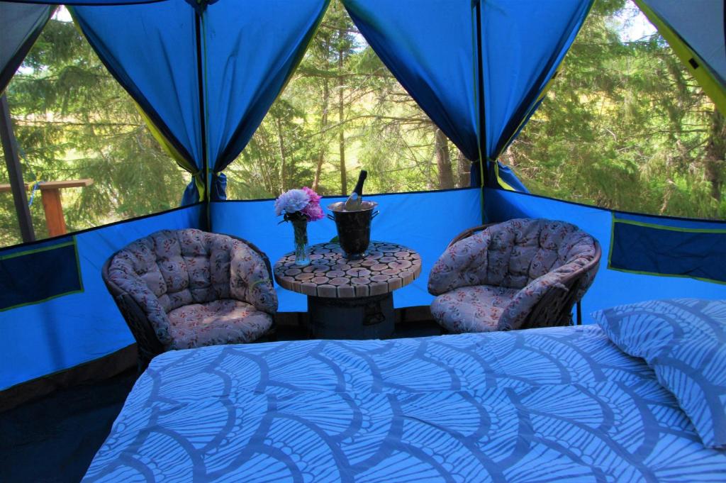 a room with two chairs and a bed in a tent at Puumaja maaseudulla in Tuorila
