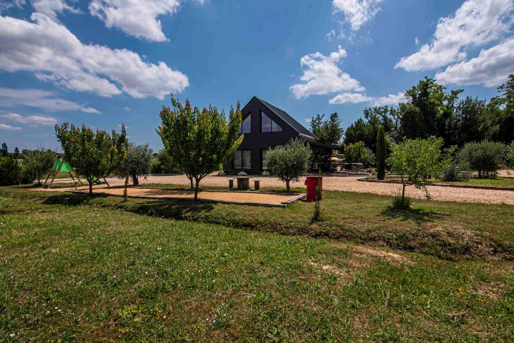 uma casa num campo com árvores à frente em Villa indépendante gîte Mas fond des Prés em Saint-Privat-des-Vieux