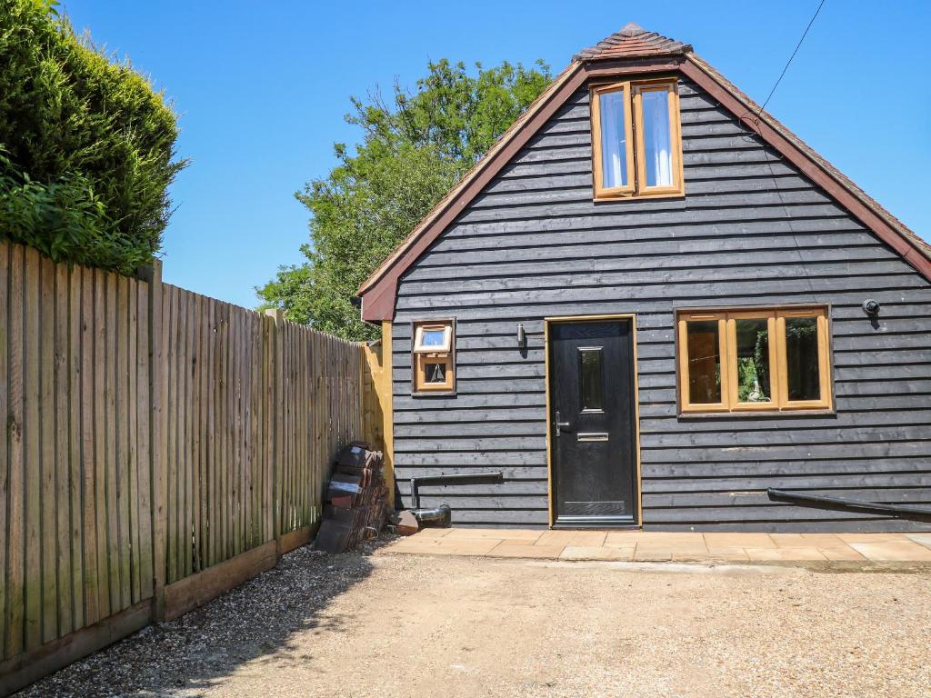 una pequeña casa con una puerta negra y una valla en Foxes Earth en Salisbury