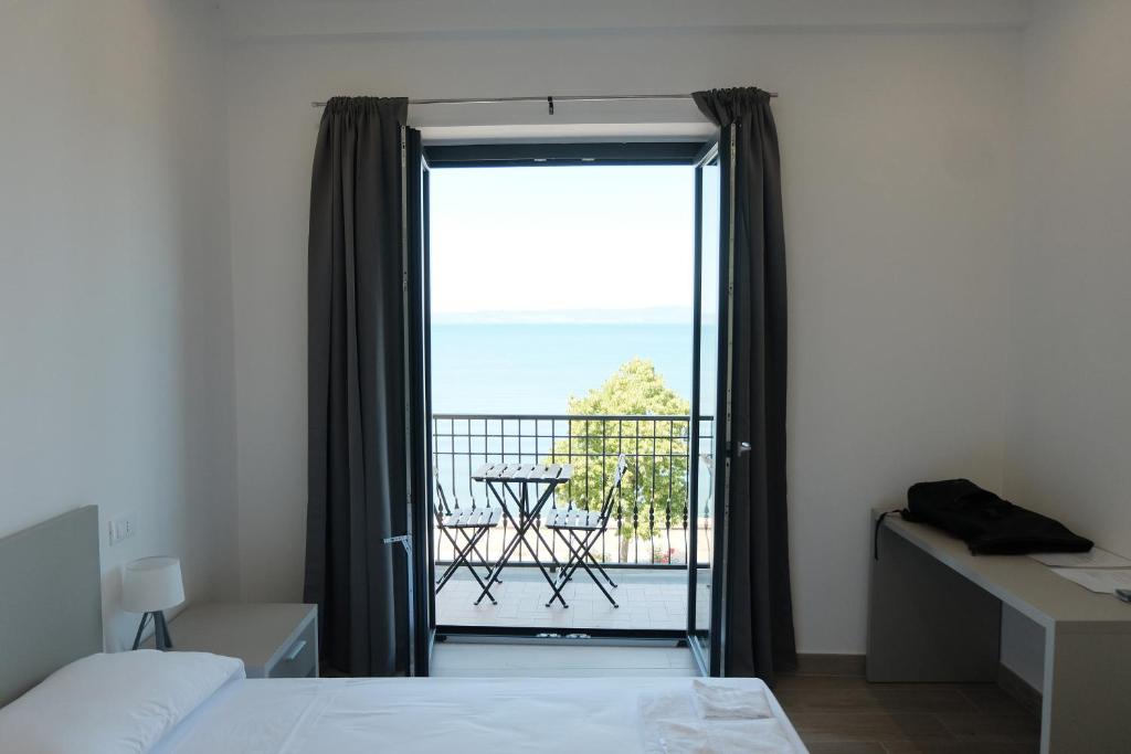 a bedroom with a bed and a glass door with a balcony at Like Lake Bisentina in Marta