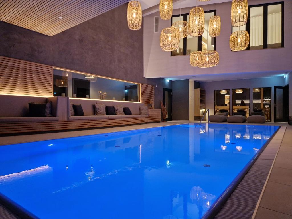 a swimming pool in a hotel with chandeliers at Landhotel Rittmeister & Kräuter-SPA Adults Only in Rostock