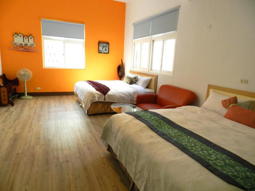 two beds in a room with orange walls and wooden floors at Home in Hengchun Homestay in Hengchun South Gate