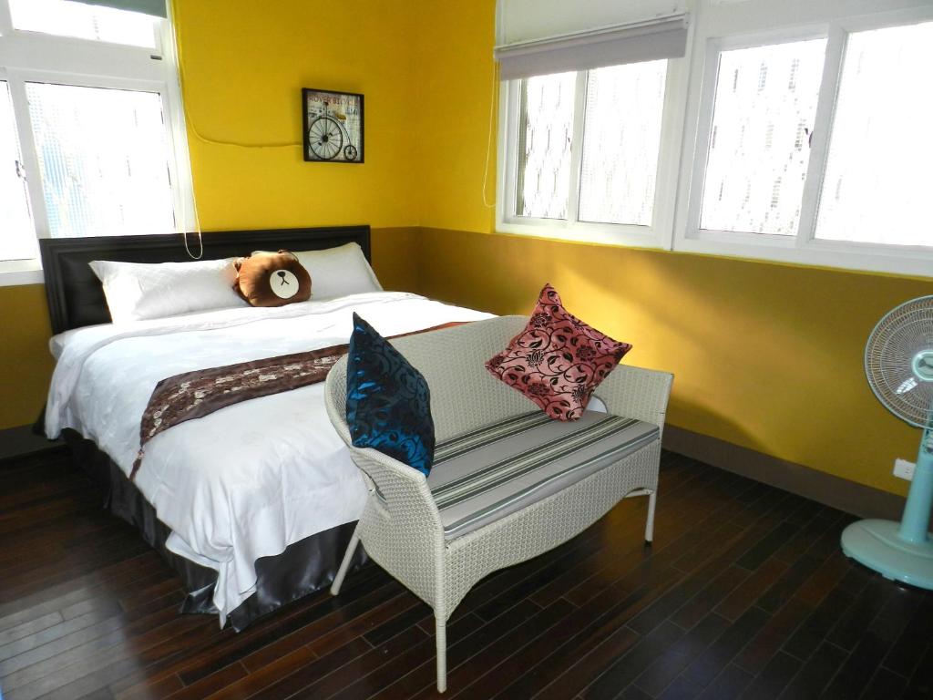 a bedroom with a bed and a chair and windows at Home in Hengchun Homestay in Hengchun South Gate