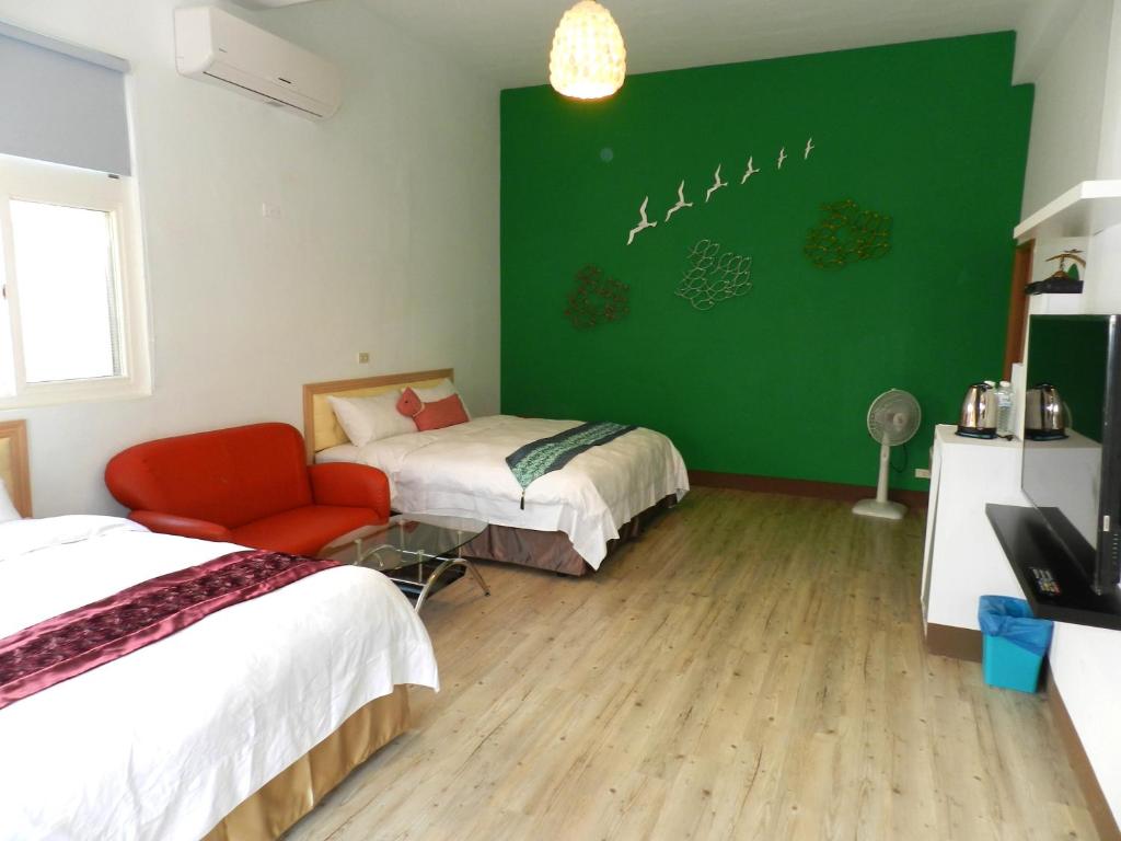 a room with two beds and a green wall at Home in Hengchun Homestay in Hengchun South Gate