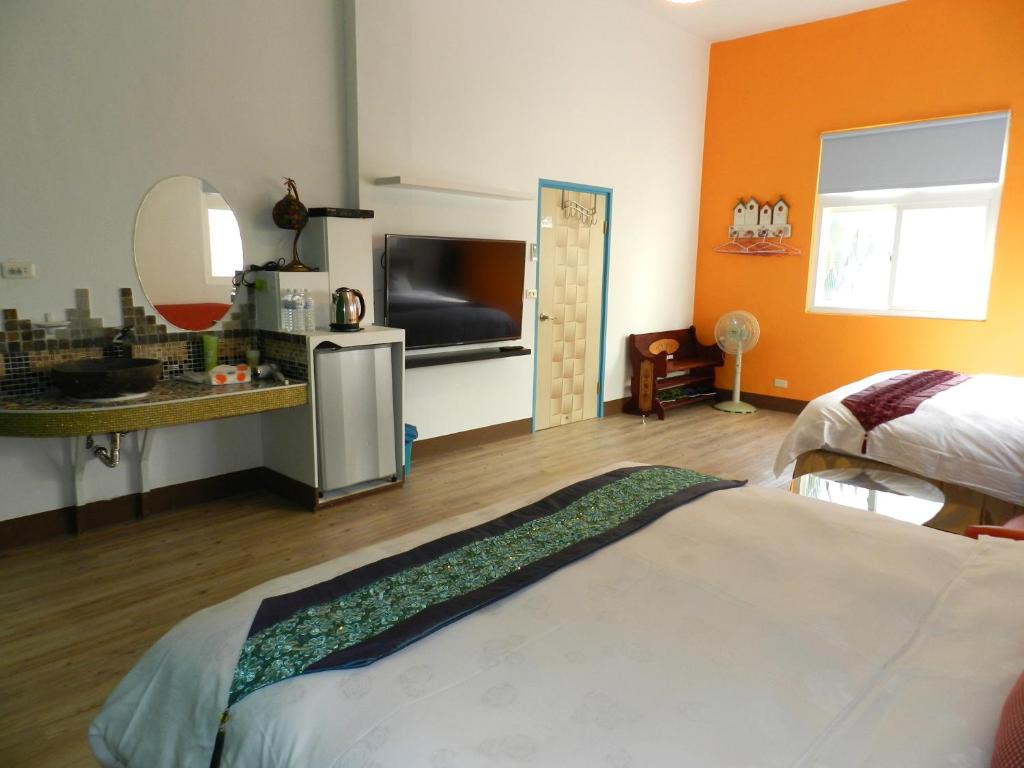 a bedroom with orange walls and a bed and a flat screen tv at Home in Hengchun Homestay in Hengchun South Gate