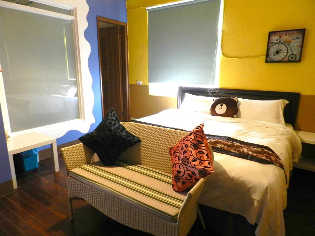 a bedroom with a bed and a bench with pillows at Home in Hengchun Homestay in Hengchun South Gate