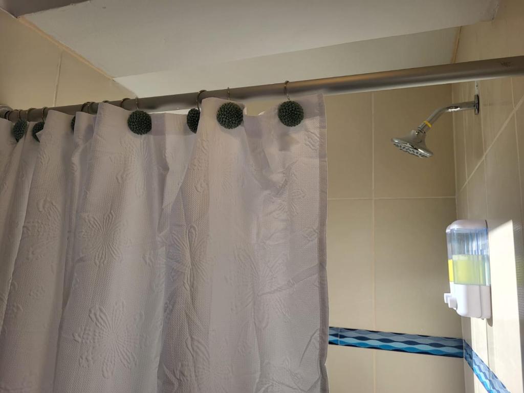 y baño con ducha con cortina blanca. en Vértigo Valle Sagrado, en Urubamba