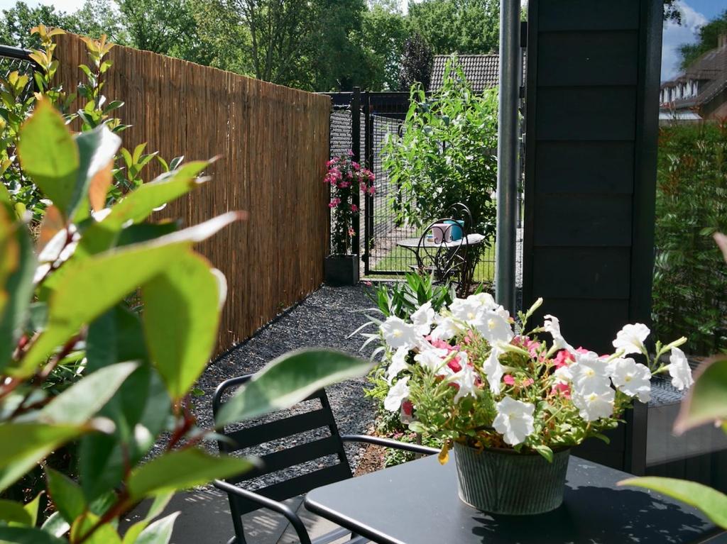 a table with a vase of flowers on a patio at Bed & Breakfast Udens Buiten in Veghel