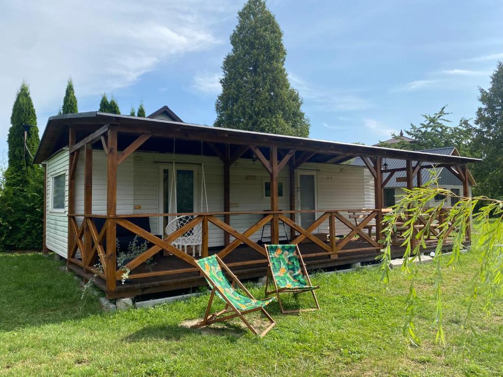 a house with two chairs in front of it at Domek z widokiem na las in Nielisz