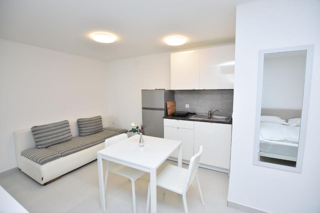 a white room with a table and a bed at Apartments Leonardo in Primošten