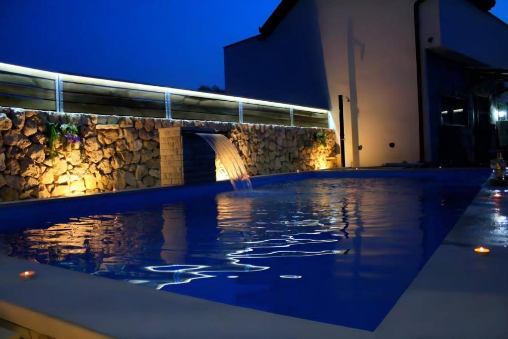 a swimming pool with a fountain at night at Estate - Villa Discovery in Ljubuški