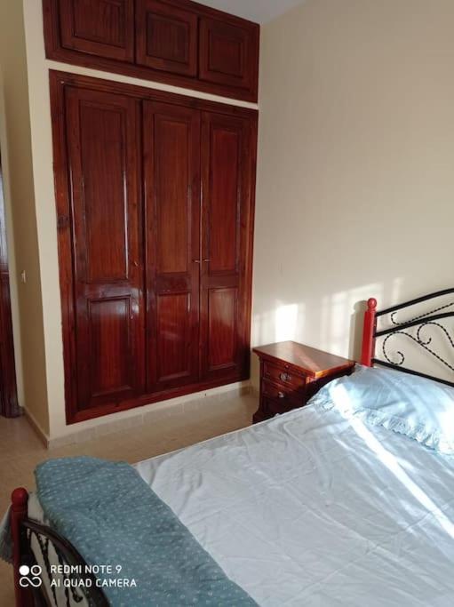 um quarto com uma cama e um armário de madeira em Grand appartement à deux pas de la plage em Souira Guedima