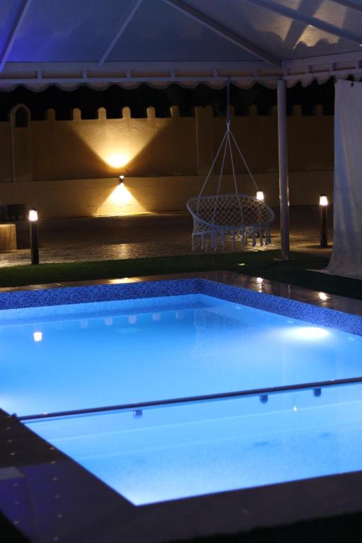 uma piscina iluminada à noite em استراحة الغيل صحار 