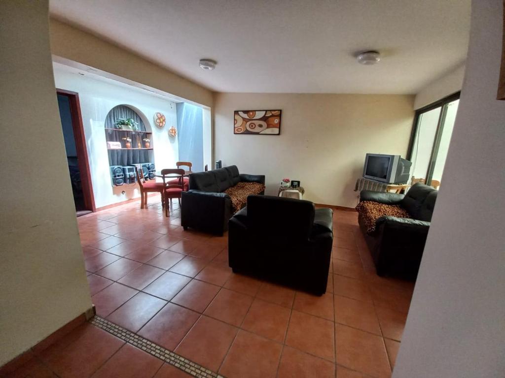 een woonkamer met zwarte banken en een televisie bij Casa Entera Gran Descanso - Wifi in Apizaco