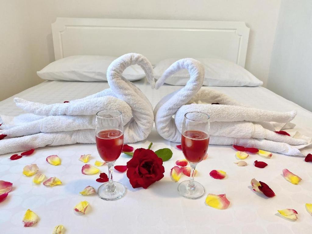 zwei Schwanenhandtücher und zwei Gläser Wein auf dem Bett in der Unterkunft Arlind's Apartaments in Vlorë