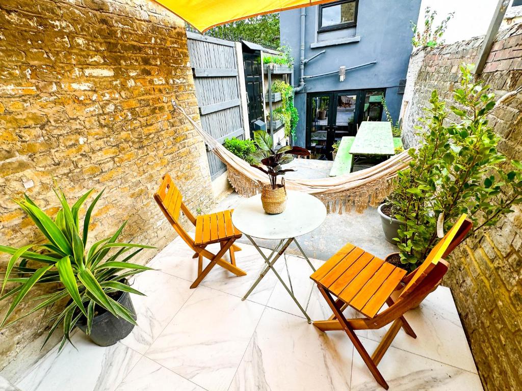 a patio with a table and chairs and plants at Modern flat with KING bed, garden & outdoor dining in London