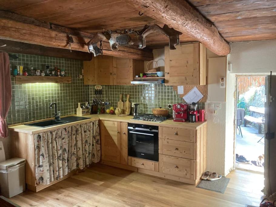 une cuisine avec des armoires en bois et un four à plaques de cuisson dans l'établissement Rustikales Haus im Naturparadies, à Saint-Étienne-de-Tinée