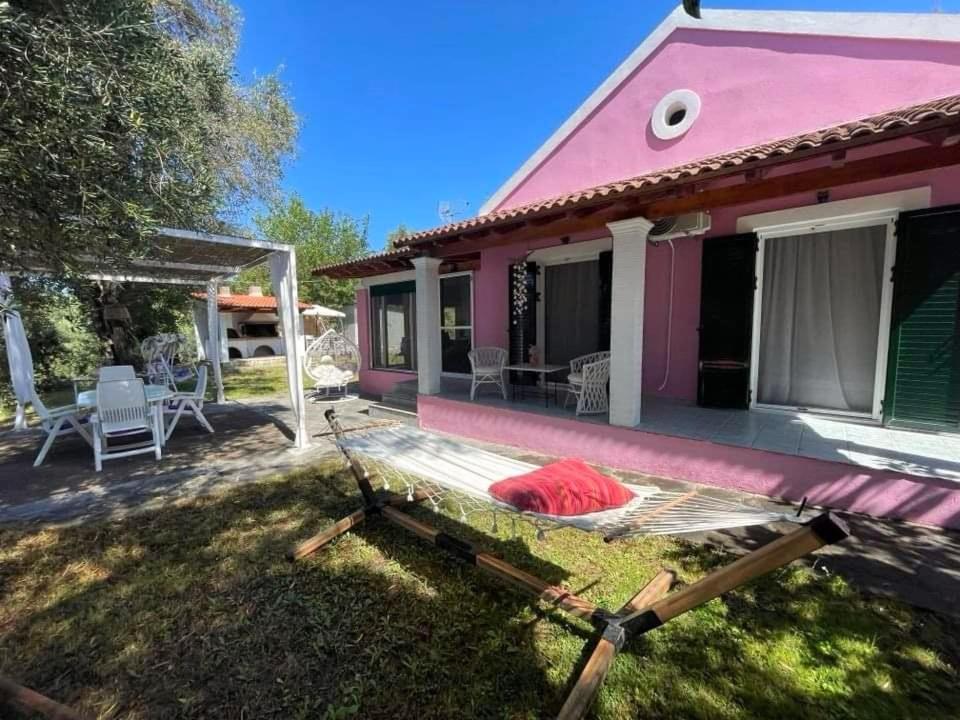 una casa rosa con terraza en el patio en Villa Penelope en Corfú