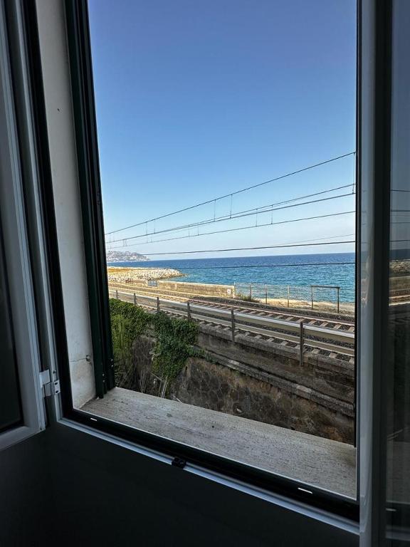 una finestra con vista sulla spiaggia di La Via Sul Mare a Bordighera
