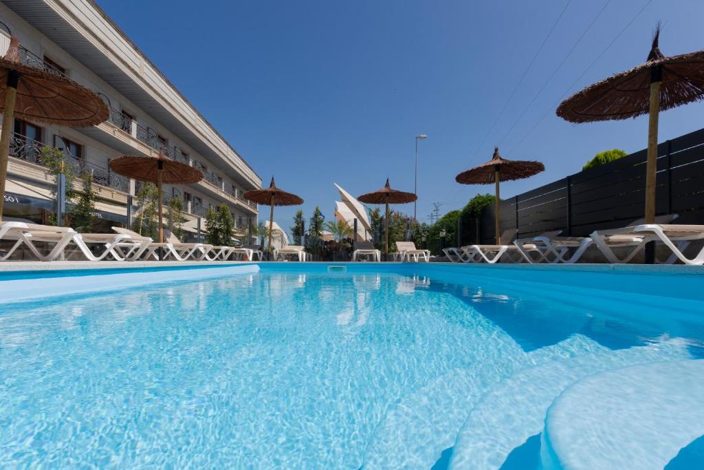 una gran piscina con sillas y sombrillas en Hotel Alfonso I, en Tui