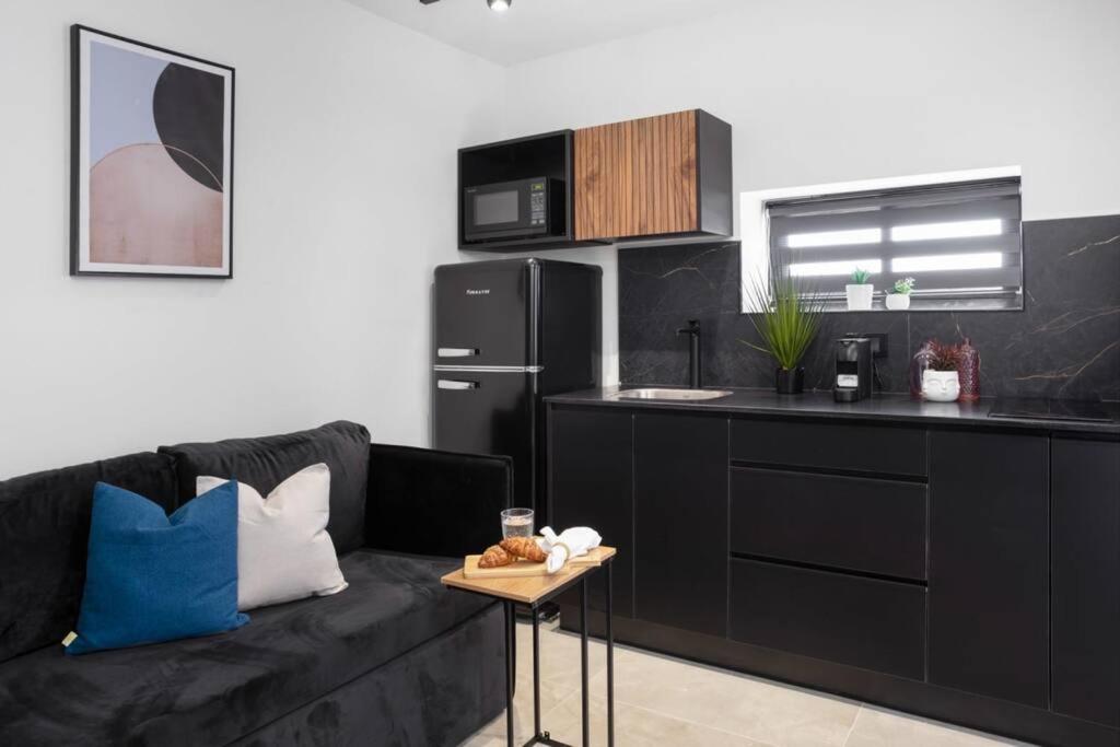ein Wohnzimmer mit einem schwarzen Sofa und einer Küche in der Unterkunft By Eezy - דירת נופש עם חדר שינה אחד במיקום מעולה Ashram 3 in Eilat