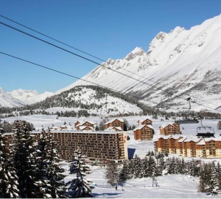 un lodge de ski dans la neige avec une montagne dans l'établissement Logement au pied des pistes Superdevoluy, à Saint-Étienne-en-Dévoluy