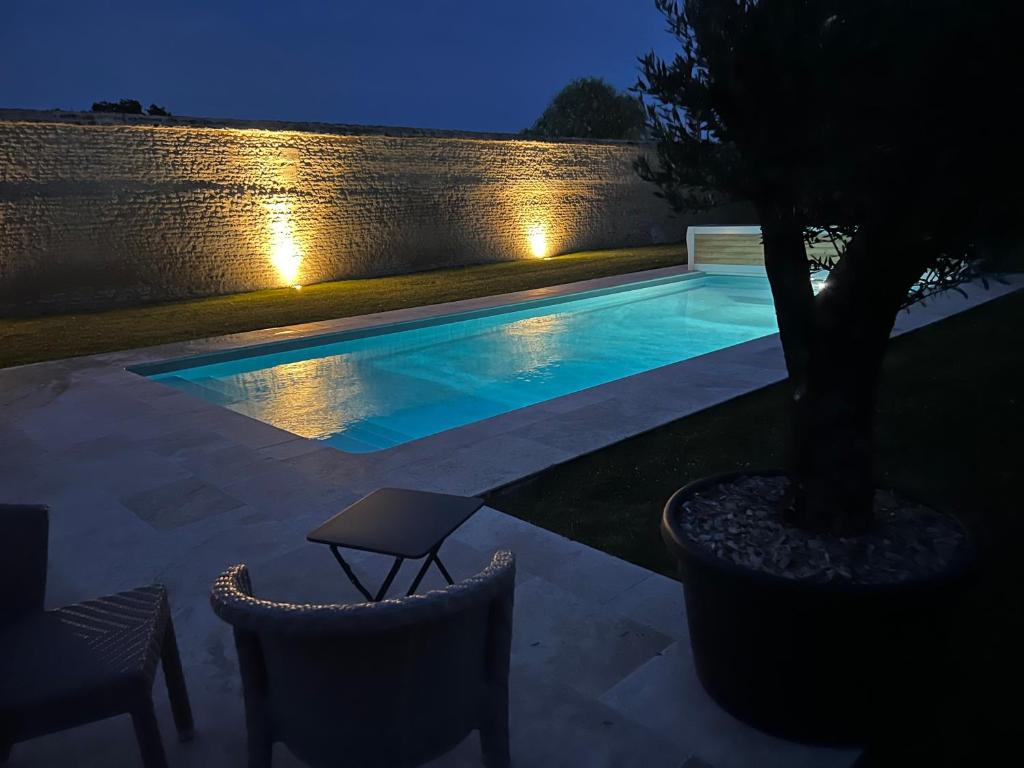 uma piscina à noite com uma árvore e luzes em Gîte du Manoir de Berville em Saint-Pierre-sur-Dives