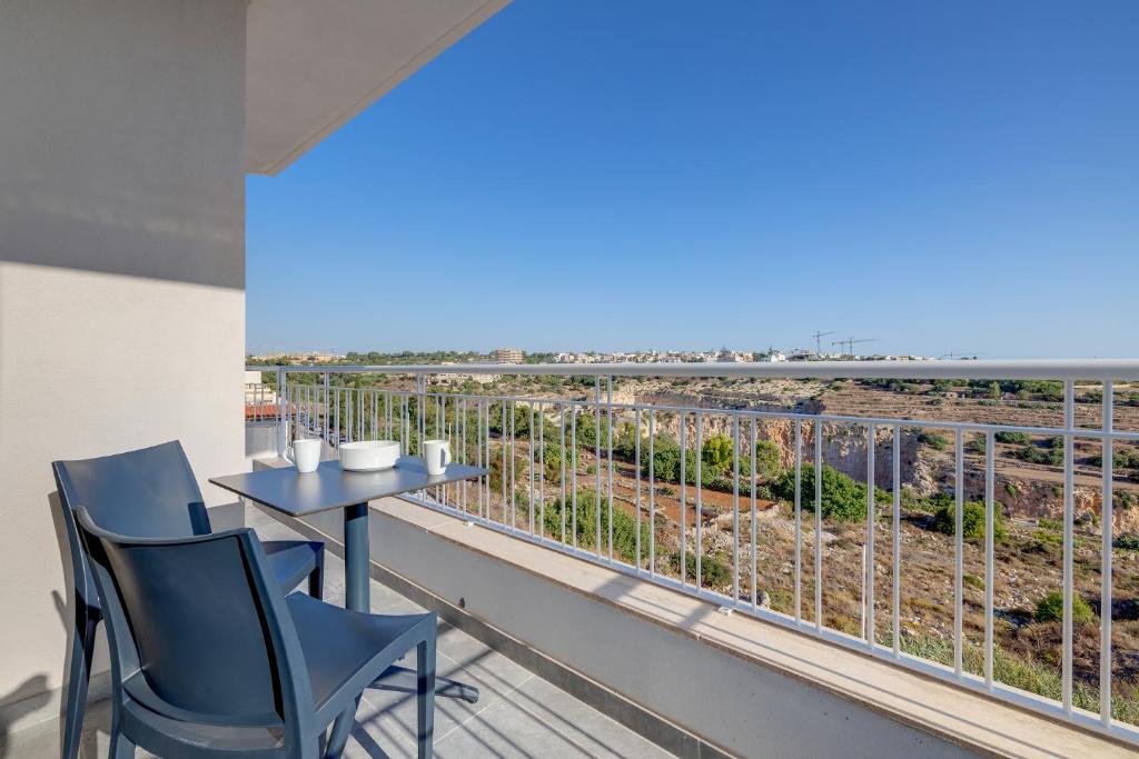 einen Balkon mit einem Tisch und Stühlen sowie Meerblick in der Unterkunft Valley's Edge Apartments in San Ġwann