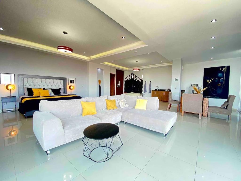 a living room with a white couch and a bed at Suites La Gloria Alojamiento independiente in Tepatitlán de Morelos