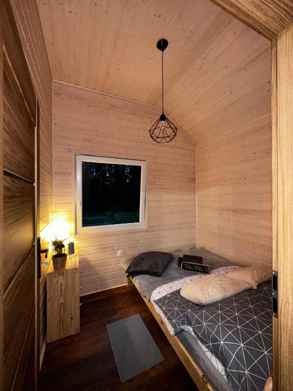 Small wooden room with bed, window, and warm lighting.