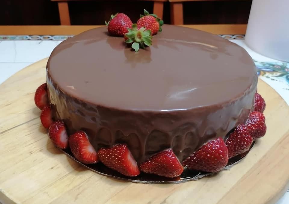 a chocolate cake with strawberries on a wooden table at Ionian residence in Argostoli