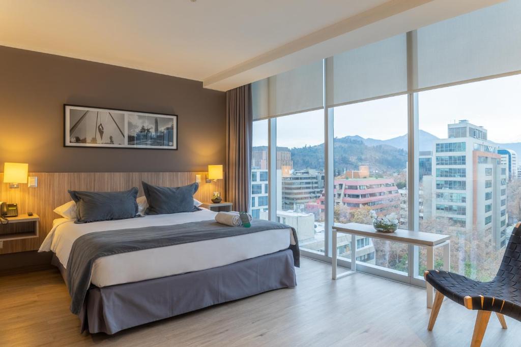 ein Hotelzimmer mit einem Bett und einem großen Fenster in der Unterkunft Hotel Capital Bellet in Santiago