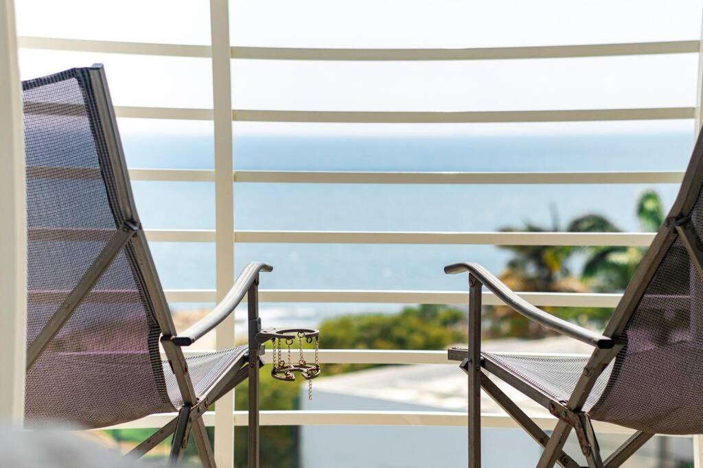 2 stoelen op een balkon met uitzicht op de oceaan bij Dpto frente al mar, piscina, check in automático in Playas