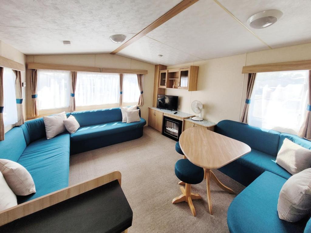 ein Wohnzimmer mit einem blauen Sofa und einem Tisch in der Unterkunft The Burrow - 152 Mallard Lake in South Cerney
