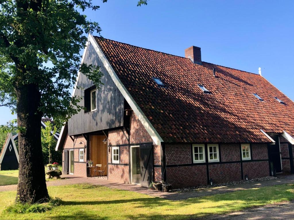 an old house with a red roof and a tree at LooSan Lodges in Reutum